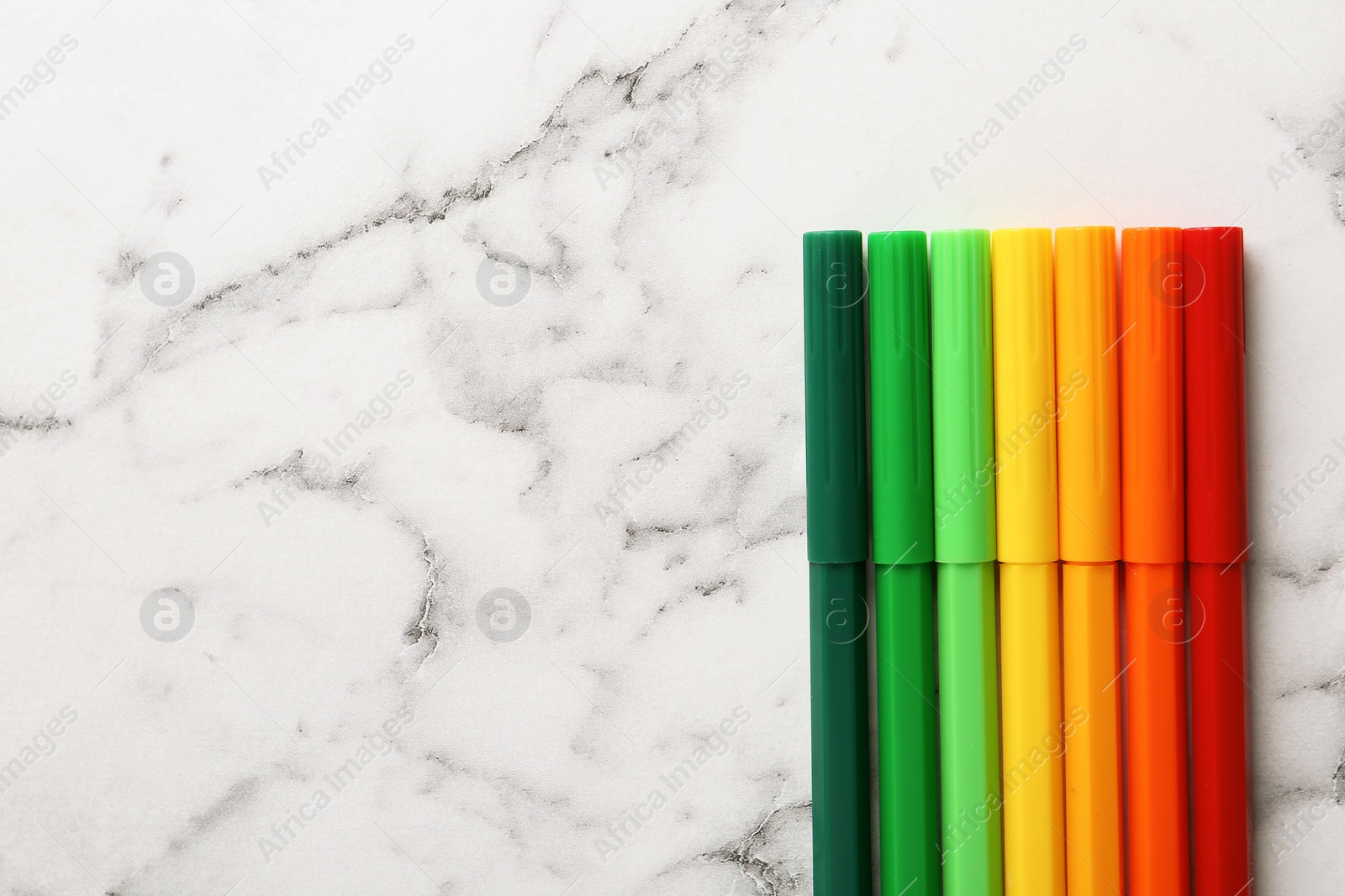 Photo of Colorful markers on white marble background, flat lay with space for text. Energy efficiency concept