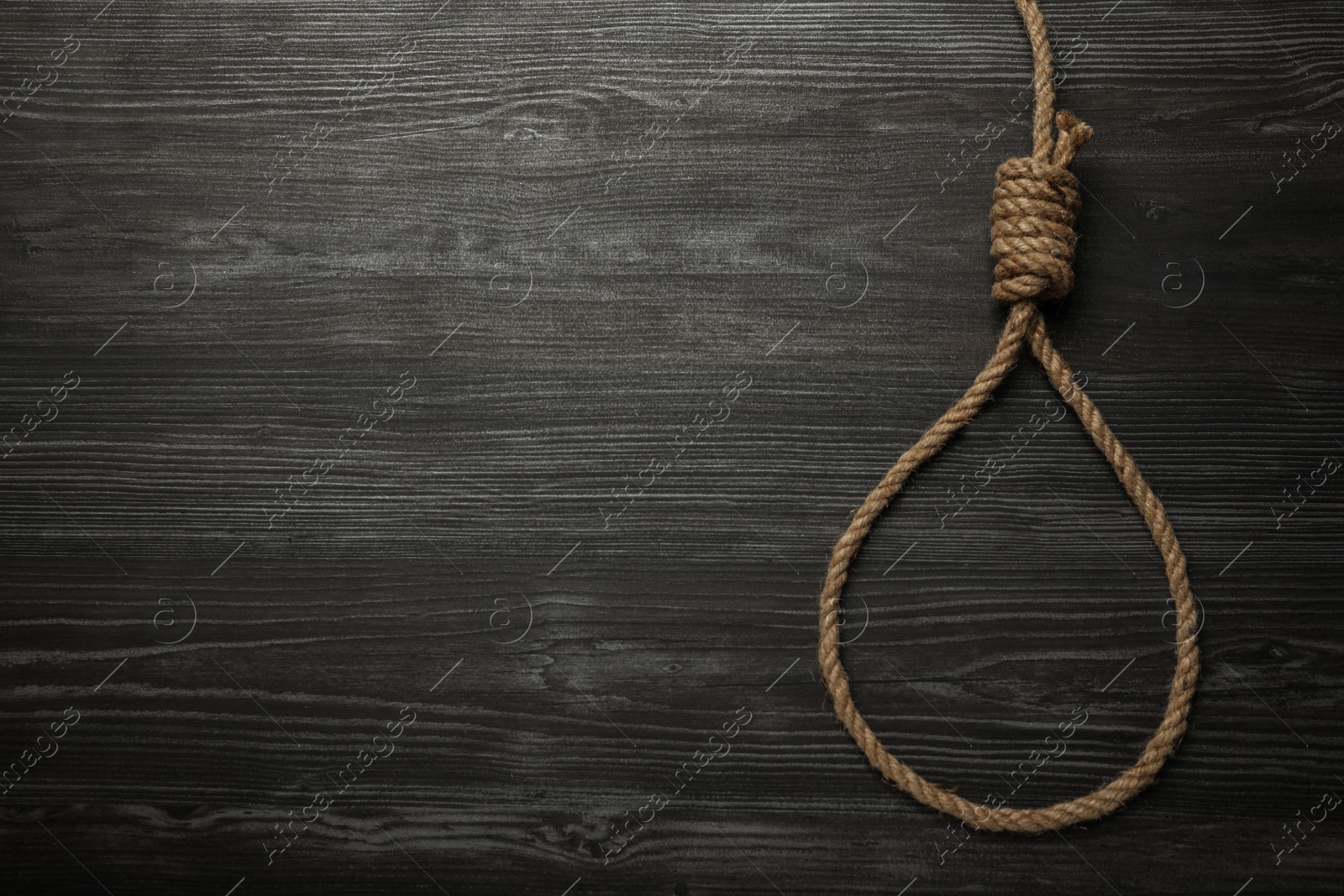 Photo of Rope noose on black wooden table, top view. Space for text