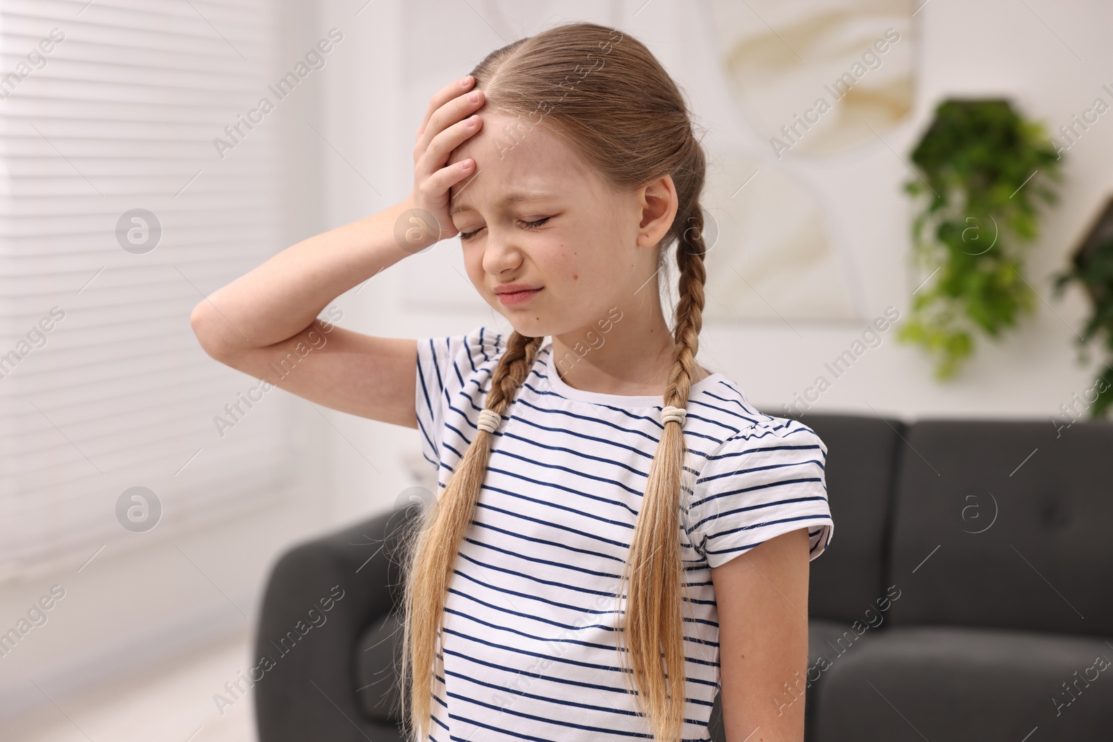 Photo of Little girl suffering from headache at home