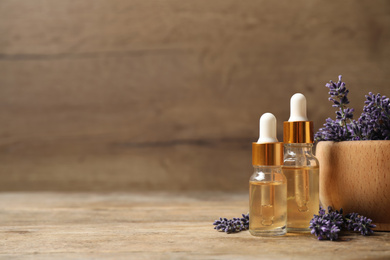 Photo of Beautiful lavender flowers and natural essential oil on wooden table. Space for text