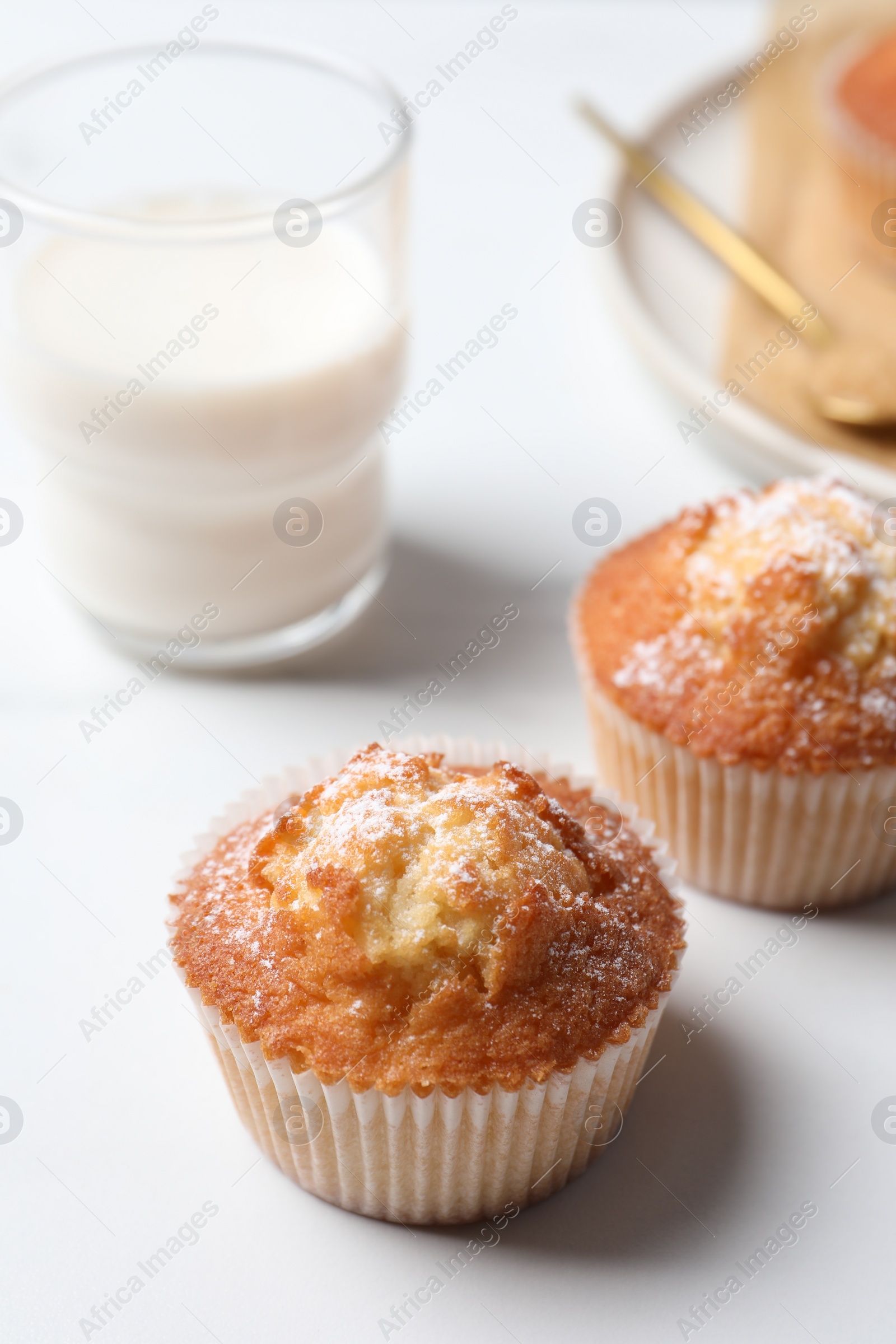 Photo of Delicious sweet muffins and glass of milk on white table, closeup