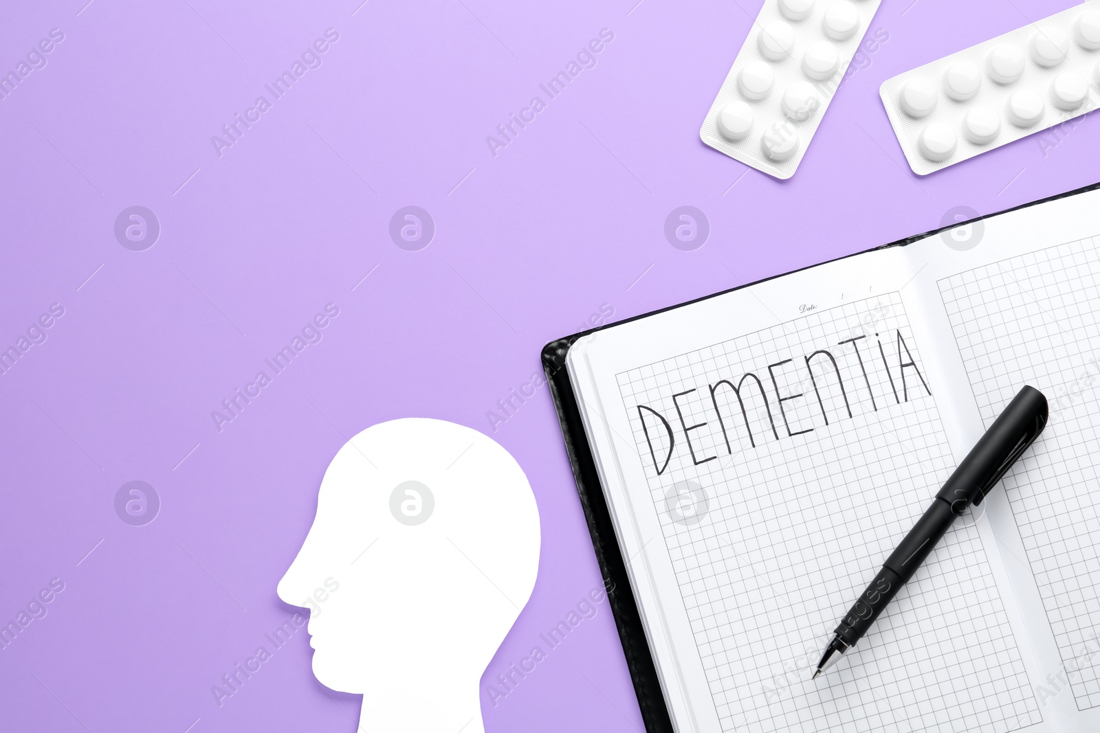 Photo of Notebook with word Dementia, pills and human head cutout on violet background, flat lay. Space for text