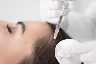 Young woman with hair loss problem receiving injection in salon, closeup