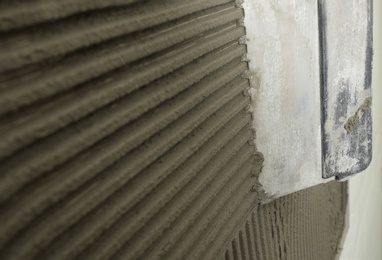 Photo of Spreading concrete on wall with spatula, closeup. Space for text