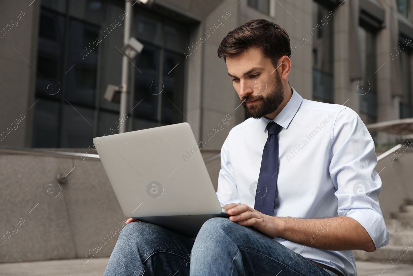 Photo of Handsome man working with laptop on city street