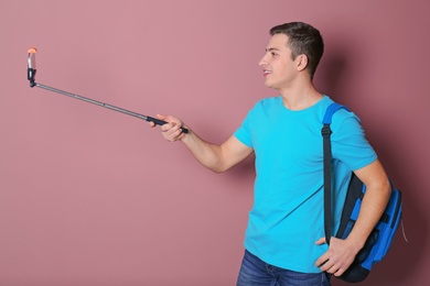 Young handsome man taking selfie against color background