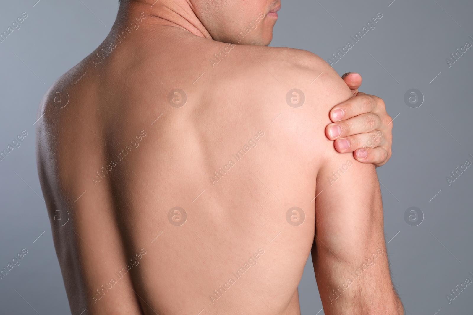 Photo of Man suffering from shoulder pain on grey background, closeup