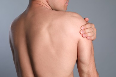 Photo of Man suffering from shoulder pain on grey background, closeup