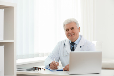 Portrait of senior doctor in white coat at workplace