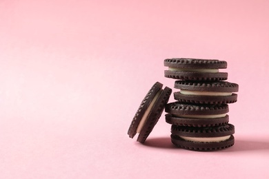 Photo of Tasty chocolate cookies with cream on color background. Space for text