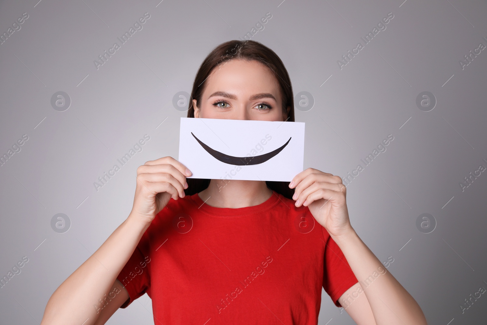 Photo of Woman holding sheet of paper with smile on grey background