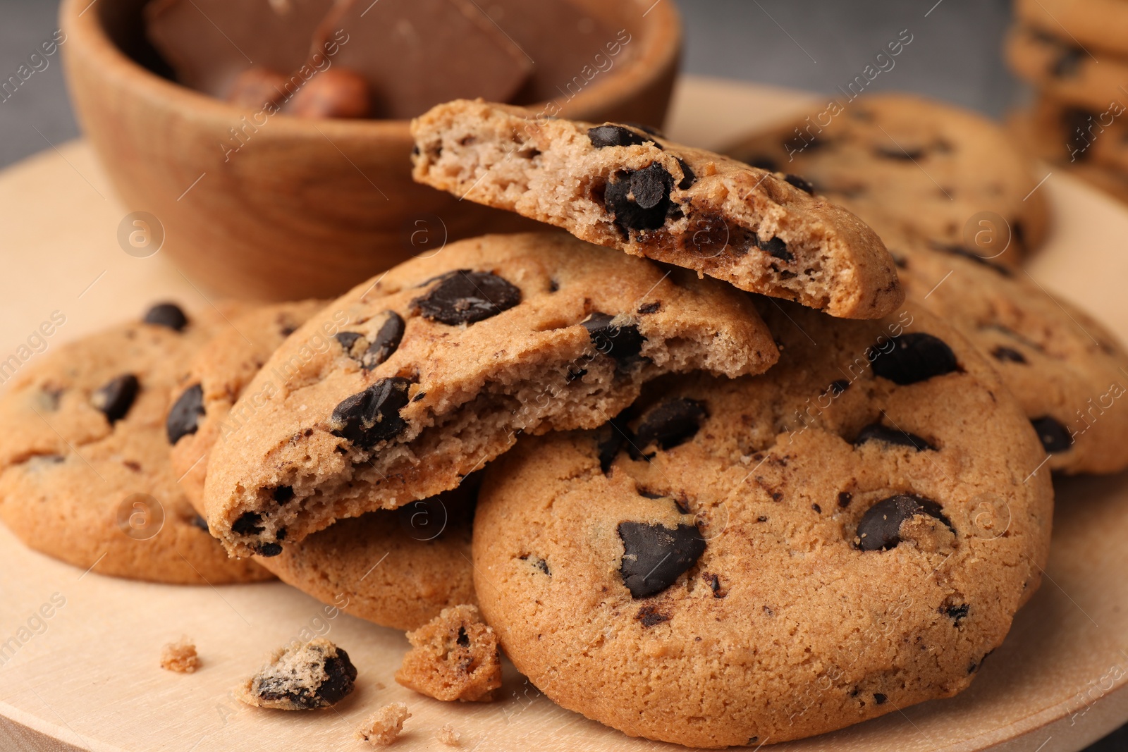 Photo of Delicious chocolate chip cookies on wooden tray, closeup