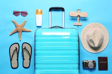 Photo of Flat lay composition with suitcase and beach objects on blue background