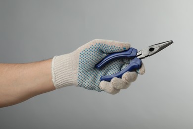 Man with needle nose pliers on grey background, closeup