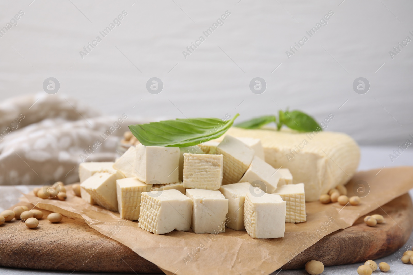 Photo of Delicious tofu cheese, basil and soybeans on wooden board, closeup