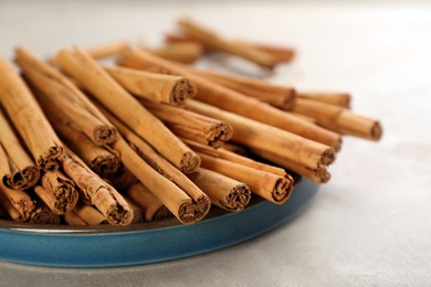 Photo of Aromatic cinnamon sticks on grey table, closeup