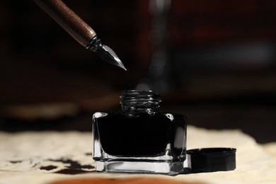 Photo of Fountain pen near inkwell on vintage parchment, closeup