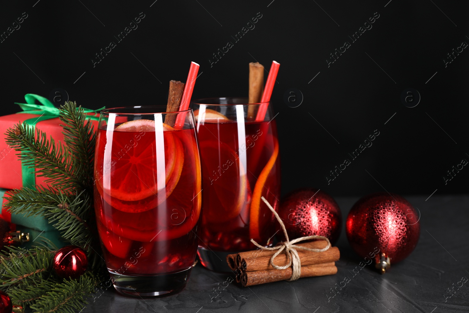 Photo of Delicious Sangria drink in glasses and Christmas decorations on dark textured table, closeup