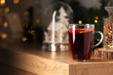 Delicious mulled wine in glass cup on wooden table. Space for text