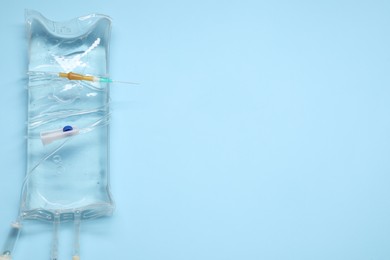 Photo of IV infusion set on light blue background, top view. Space for text