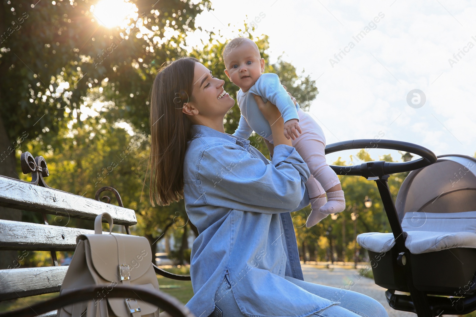 Photo of Young mother with her baby on bench in park