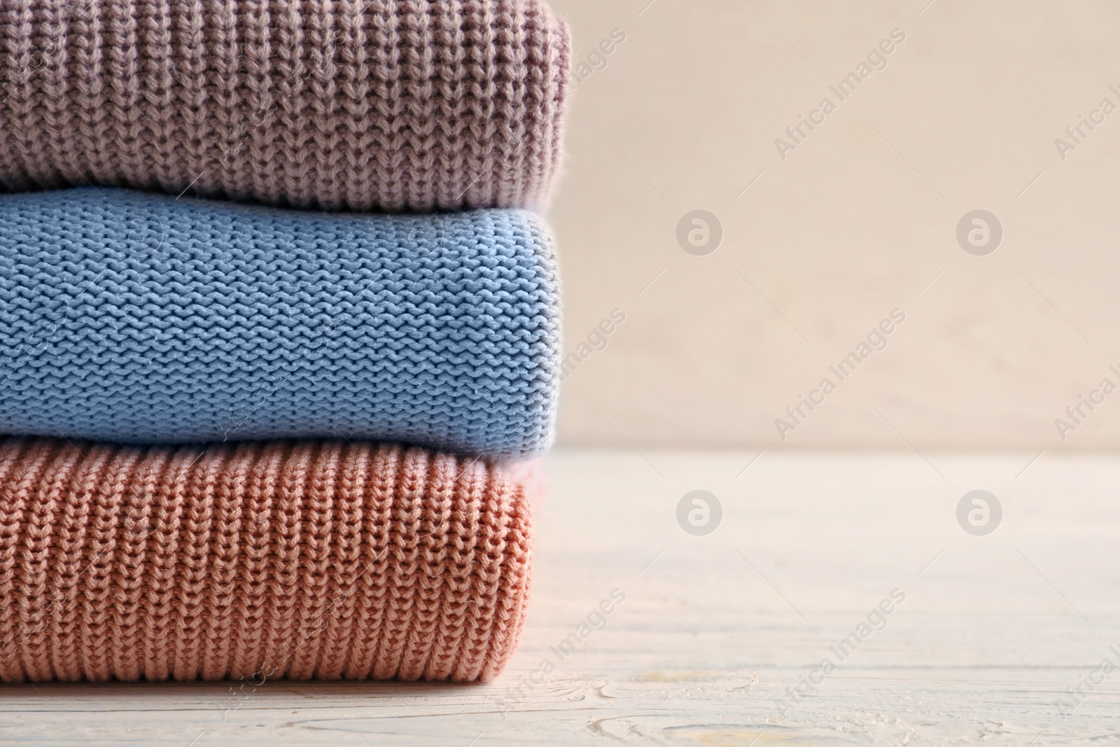 Stack of warm knitted clothes on table Photo of Stack of warm knitted clothes on table