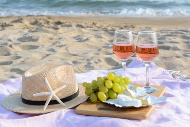 Photo of Glasses with rose wine and snacks for beach picnic on sandy seashore