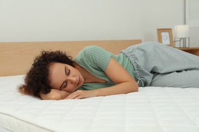 Photo of Young African American woman sleeping on bed with comfortable mattress at home