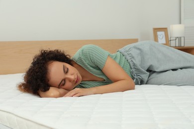 Young African American woman sleeping on bed with comfortable mattress at home