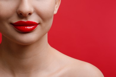 Photo of Closeup view of woman with beautiful lips on red background. Space for text