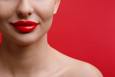 Closeup view of woman with beautiful lips on red background. Space for text