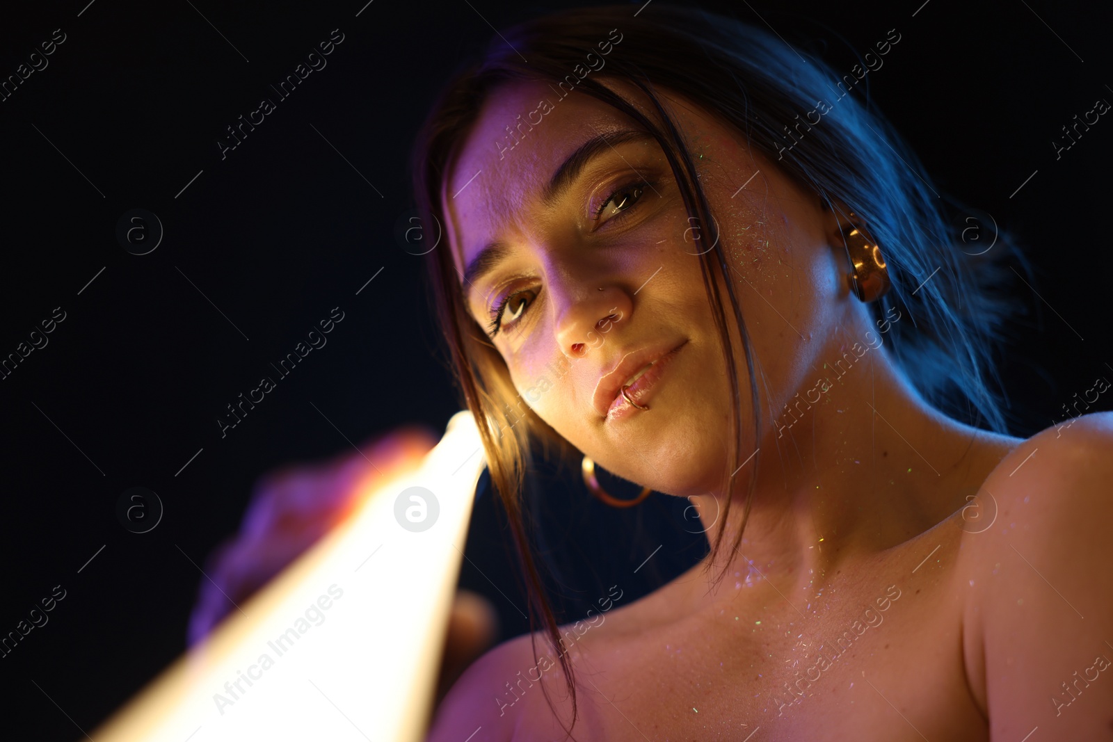 Photo of Beautiful woman with lamp on dark background in neon lights