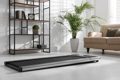 Photo of Modern walking treadmill in living room. Home gym equipment