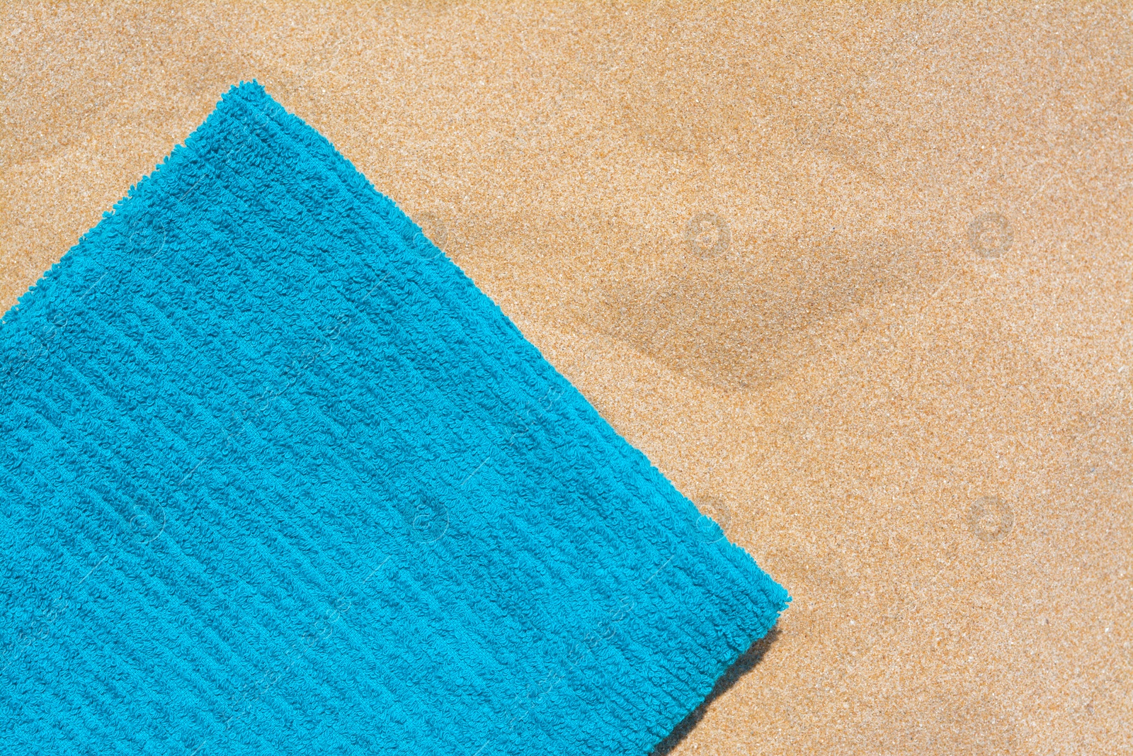 Photo of Soft blue beach towel on sand, top view. Space for text