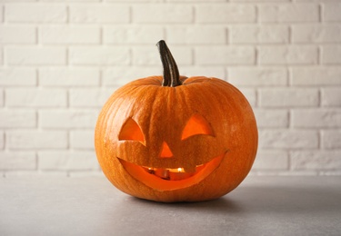 Photo of Halloween pumpkin head jack lantern on table against brick wall