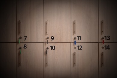 Many wooden lockers with keys and numbers on doors. Vignette effect