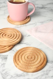 Stylish wooden cup coasters on white marble table