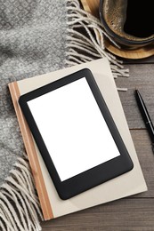 Photo of E-book reader with notebook and coffee on wooden table, flat lay. Space for text