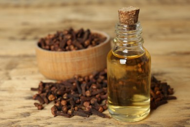 Essential oil and dried cloves on wooden table. Space for text