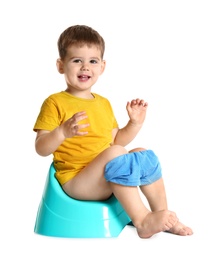 Portrait of little boy sitting on potty against white background