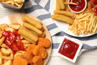 Different snacks and tasty ketchup on wooden table, flat lay