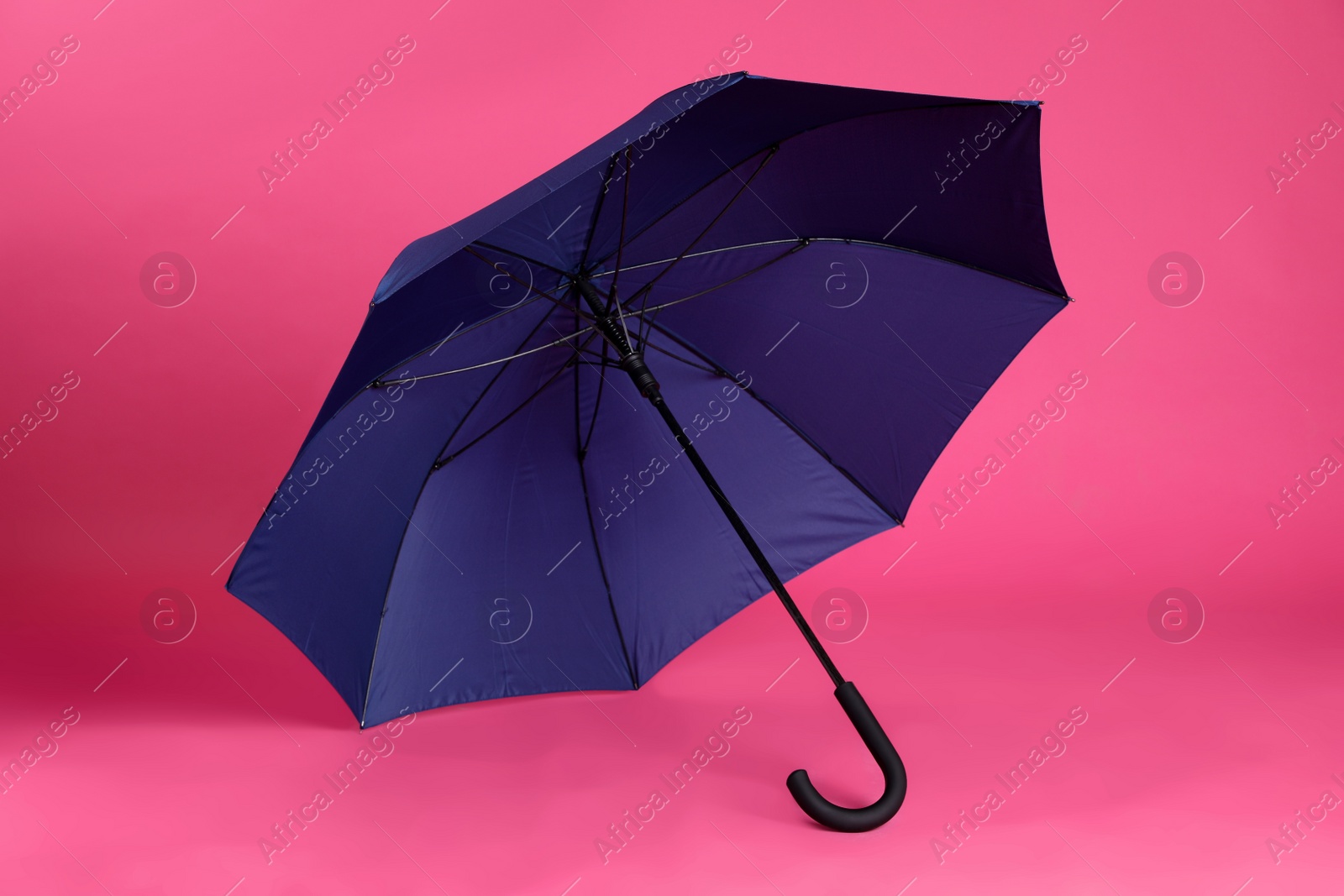 Photo of Stylish open blue umbrella on pink background