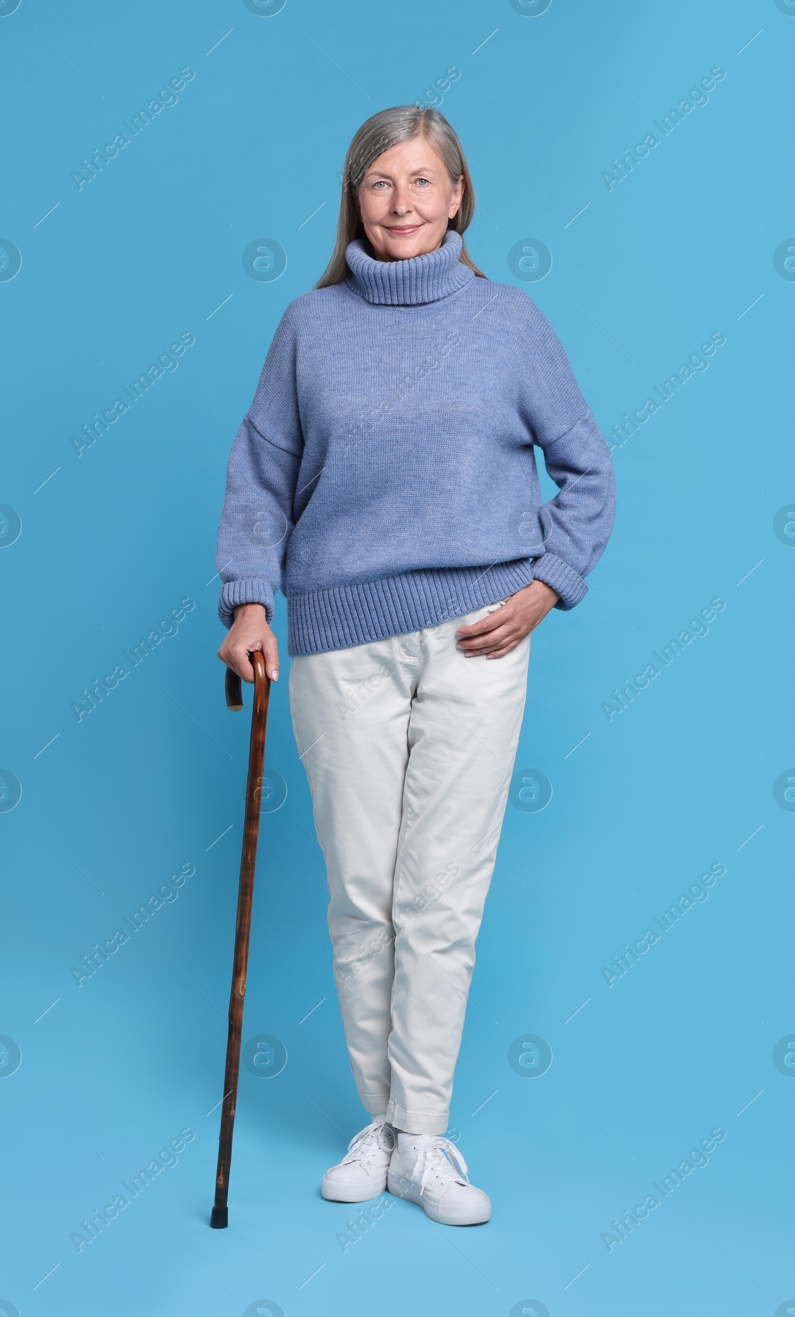 Photo of Senior woman with walking cane on light blue background