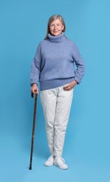 Photo of Senior woman with walking cane on light blue background