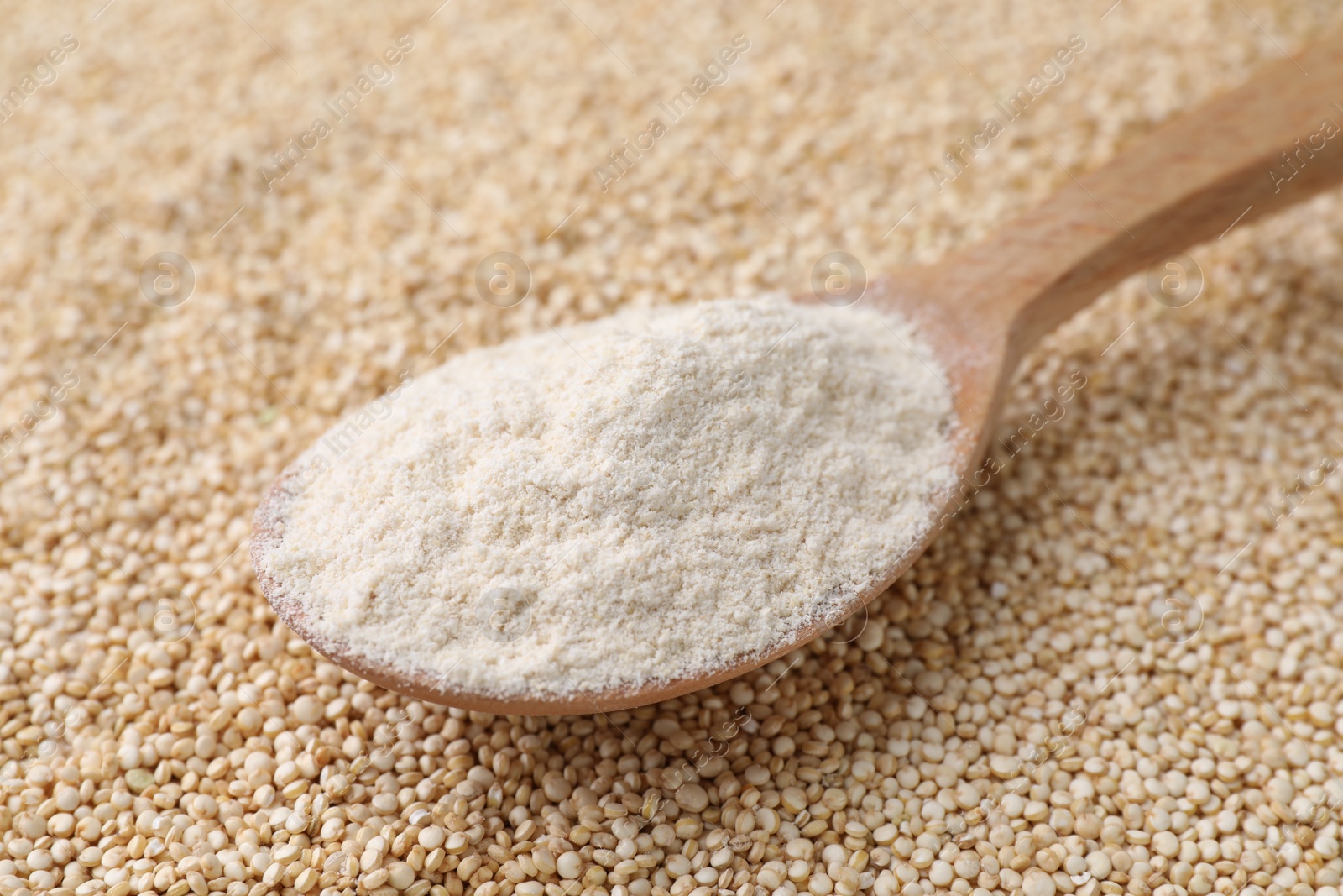 Photo of Wooden spoon with quinoa flour on seeds, closeup