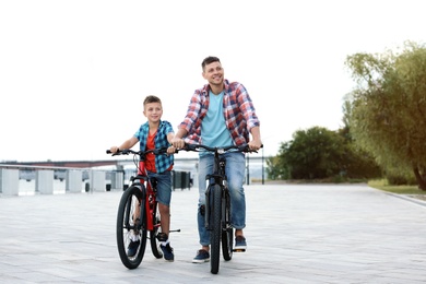 Photo of Dad and son riding bicycles together outdoors