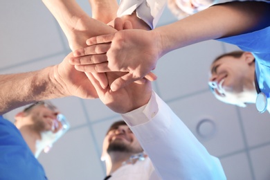 Young medical doctors putting hands together indoors, bottom view. Unity concept