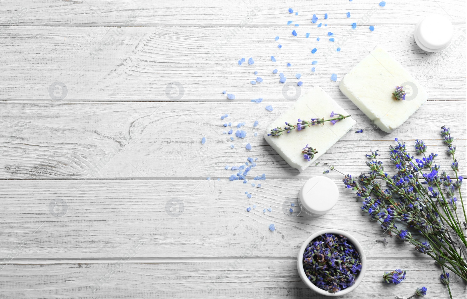 Photo of Flat lay composition of handmade soap bars with lavender flowers on white wooden background. Space for text