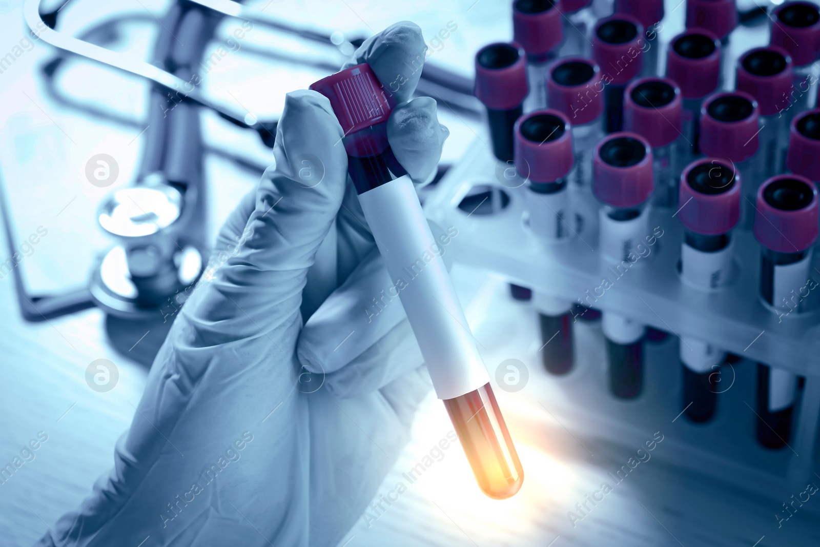 Image of Laboratory worker holding test tube with blood sample over table, closeup. Color toned