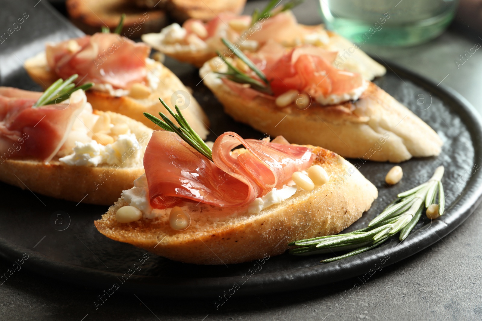 Photo of Tasty bruschettas with prosciutto and cream cheese served on table, closeup